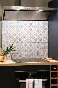 a kitchen with a tiled wall with a stove at Escale de Giulia in Beaune
