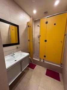 a bathroom with a sink and a shower with yellow doors at Tarragona Rooms 4 in Tarragona +22 photos