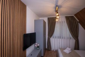 a room with a tv and a bed and a window at Cabana Casa Luca in Rănuşa