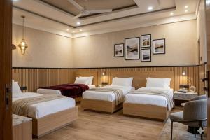 a hotel room with three beds in a room at Ajwah Hotel Bahrain in Āīn