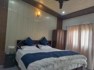a bedroom with a large bed with blue and white sheets at Pahadi aangan in Bhīm Tāl +12 photos