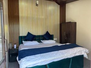 a bedroom with a large bed with blue and white sheets at Pahadi aangan in Bhīm Tāl