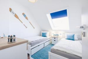 two beds in a white room with a window at Rauchschwalbe in Zingst