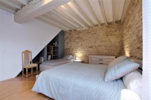a bedroom with a white bed and a brick wall at Aube au gite in Trannes +20 photos