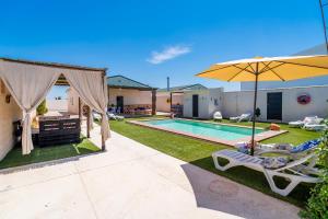 a backyard with a swimming pool and an umbrella at Casa Rural Rafael in La Lantejuela