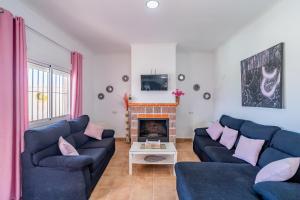 a living room with two blue couches and a fireplace at Casa Rural Rafael in La Lantejuela