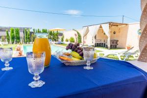 a blue table with a bowl of fruit and glasses at Casa Rural Rafael in La Lantejuela