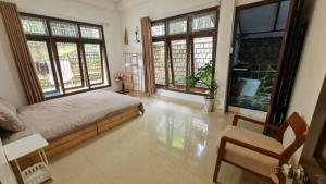 a bedroom with a bed and two windows and a chair at SugarHouse in Da Thanh