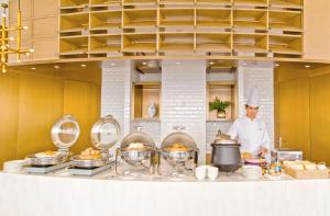 a chef standing in a kitchen with some food at Guangzhou Aiqun Hotel in Guangzhou