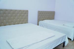 two beds in a room with white sheets at Ngày Mới Hotel in Bản Tông Duôn