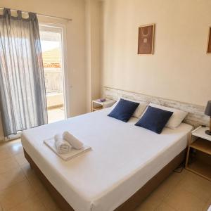 a bedroom with a large white bed with blue pillows at Meltemi Studios Polychrono in Polychrono