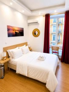 a bedroom with a large white bed with red curtains at Residence Akantha in Nice