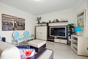 a living room with a couch and a tv at Brisa Do Mar Moura Beach in Quarteira