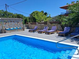 a swimming pool with purple chairs and a patio at KT Villa in Troulos