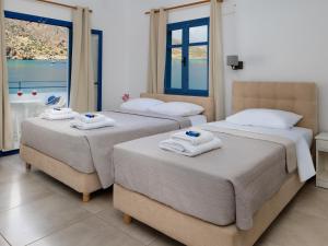 two beds in a hotel room with towels on them at Sifis in Loutro