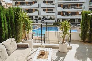 an apartment patio with a pool and palm trees at Xava Dreams Aire in Villacosta