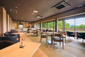 a restaurant with tables and chairs and windows at Onyado Satsuki in Tamana