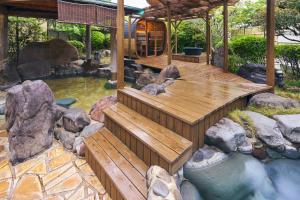 a wooden deck with a pond in a garden at Onyado Satsuki in Tamana