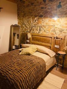 a bedroom with a bed and a stone wall at Las Riendas II La Casina in Muñeca