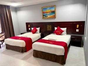 two beds in a hotel room with red pillows at Hotel Thiên Hồng in Phú Quốc