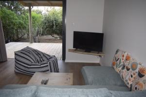 a living room with a couch and a flat screen tv at Seals Tides - sleeps 12 in Cape St Francis