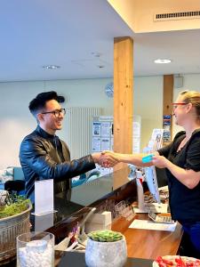 a man and a woman shaking hands at a counter at Vitalhotel Quellengarten - Bed & Breakfast in Lingenau +67 photos