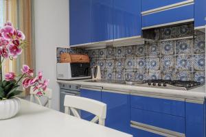 a blue kitchen with blue cabinets and a white table at Il Balcone su Tavolara in Porto San Paolo
