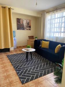 ein Wohnzimmer mit einem blauen Sofa und einem Tisch in der Unterkunft Quiet Comforts in Embu