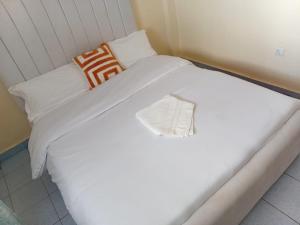 ein Bett mit weißen Laken und Kissen in einem Zimmer in der Unterkunft Quiet Comforts in Embu