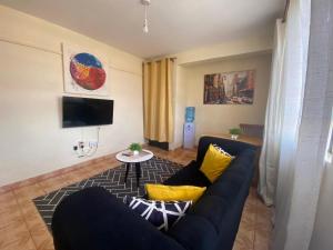 ein Wohnzimmer mit blauem Sofa und gelben Kissen in der Unterkunft Quiet Comforts in Embu