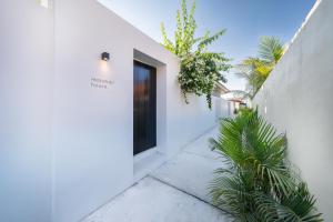 a white house with a black door and some plants at Matahari House in Nusa Lembongan