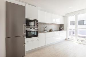 a kitchen with white cabinets and a stainless steel refrigerator at Ardantza Bidea - baskeyrentals in Zumaia