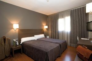a hotel room with two beds and a television at Hotel Cisneros in Alcalá de Henares