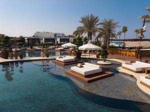 a large swimming pool with lounge chairs and umbrellas at Nikki Beach Resort & Spa Dubai in Dubai