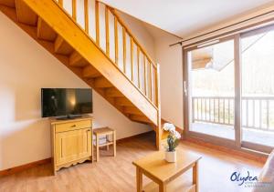 a living room with a television and a staircase at Olydea les Bottieres - Saint-Pancrace in Saint-Pancrace