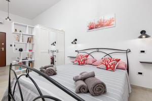 a bedroom with a bed with pink and grey pillows at Appartamenti Corallo e Conchiglia in Olbia
