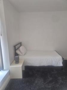a white bedroom with a bed and a night stand at Waterloo apartment in Middlesbrough +3 photos