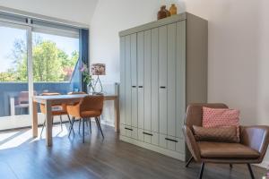 a dining room with a table and chairs and a cabinet at ParelDuyn in Oostkapelle