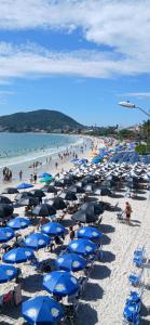 a bunch of blue umbrellas and people on a beach at 3 400m Centro de Bombinhas in Bombinhas