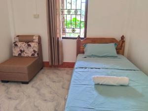 a bedroom with a bed and a chair and a window at Ban Thong hostel in Luang Prabang