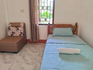 a bedroom with a bed and a chair and a window at Ban Thong hostel in Luang Prabang +5 photos