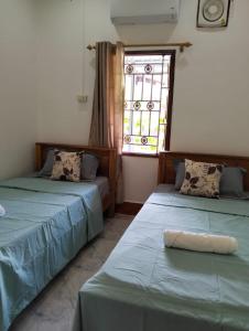 two beds in a room with a window at Ban Thong hostel in Luang Prabang