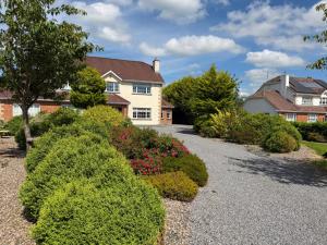 a house with bushes in front of a driveway at Tunmobi Gardens Apartment in Ballyjamesduff