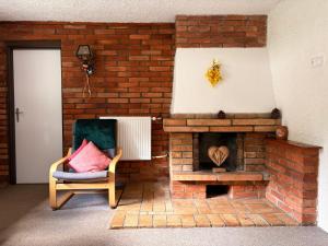a living room with a brick fireplace and a chair at Chalupa 387 in Harrachov