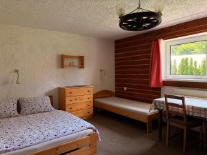 a bedroom with a bed and a desk and a window at Chalupa 387 in Harrachov