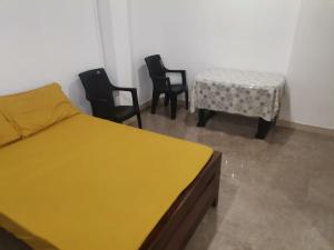 a bedroom with a bed and chairs and a table at Honey guest Batticaloa in Batticaloa