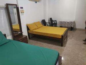 a room with a bed and a table and chairs at Honey guest Batticaloa in Batticaloa