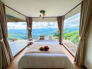 a bed in a room with a large window at ชิวชิวแคมป์ ภูชี้ฟ้า in Ban Huai Han