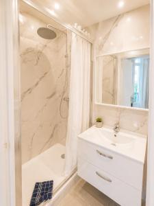 a white bathroom with a sink and a shower at Résidence Appartement Adonis in Nice +33 photos