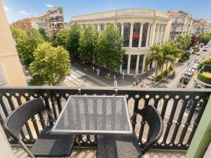 a balcony with a table and chairs on a city street at Résidence Appartement Adonis in Nice